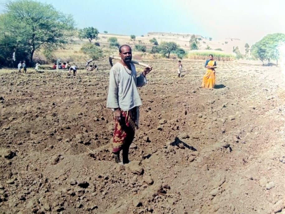 नांगरलेल्या ओसाड शेतात उभे गावकरी